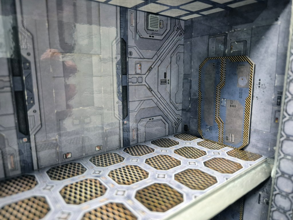 Interior of a futuristic sci-fi room with metallic walls and a patterned floor.
